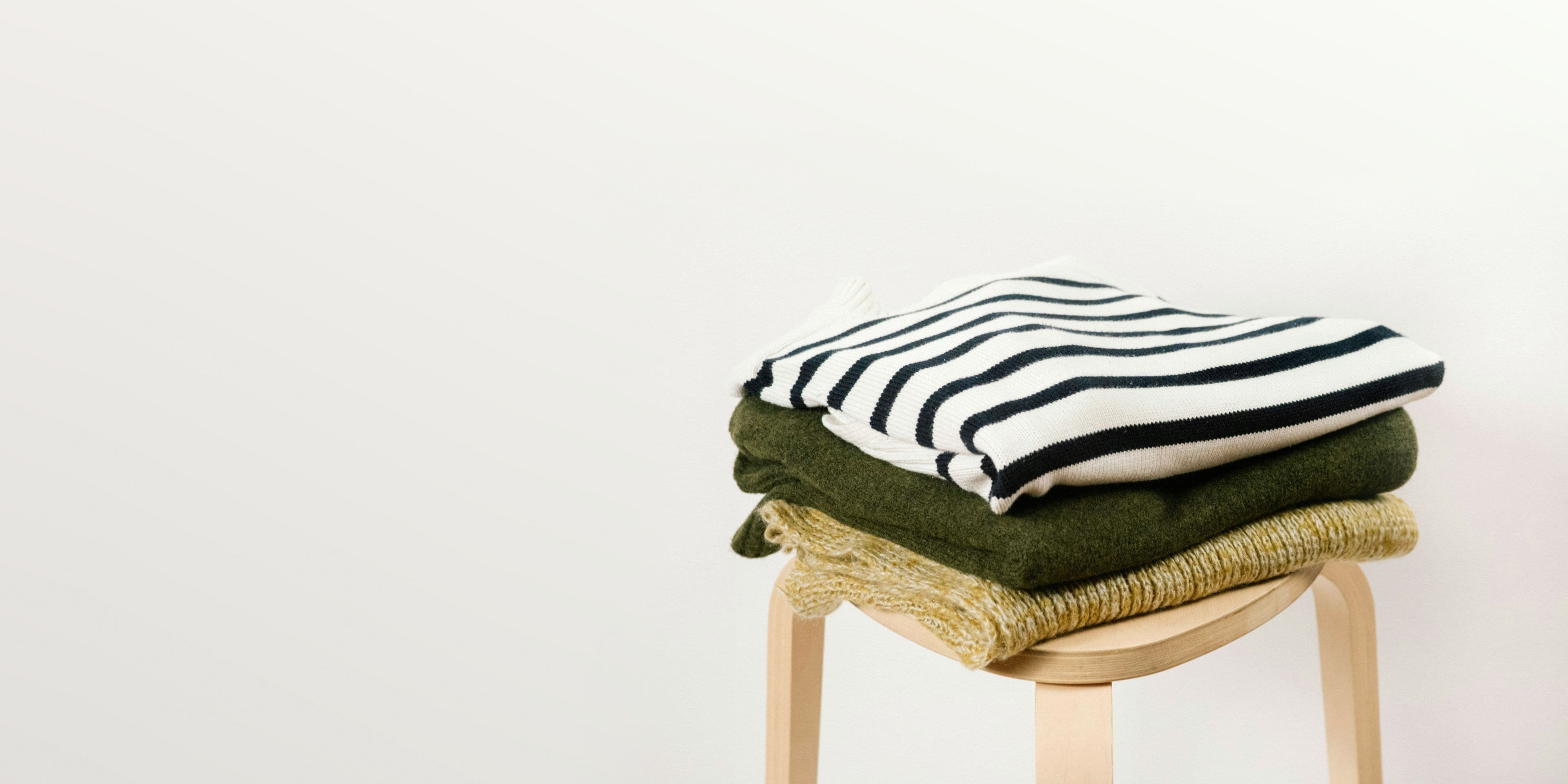 Folded wool jumpers on a wooden stool, from the Journal’s piece on wool.